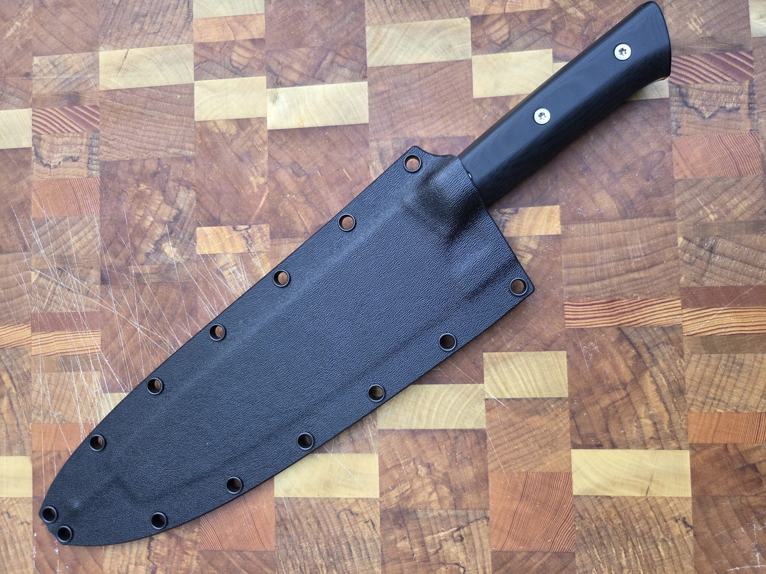 alder knife in sheath on a cutting board